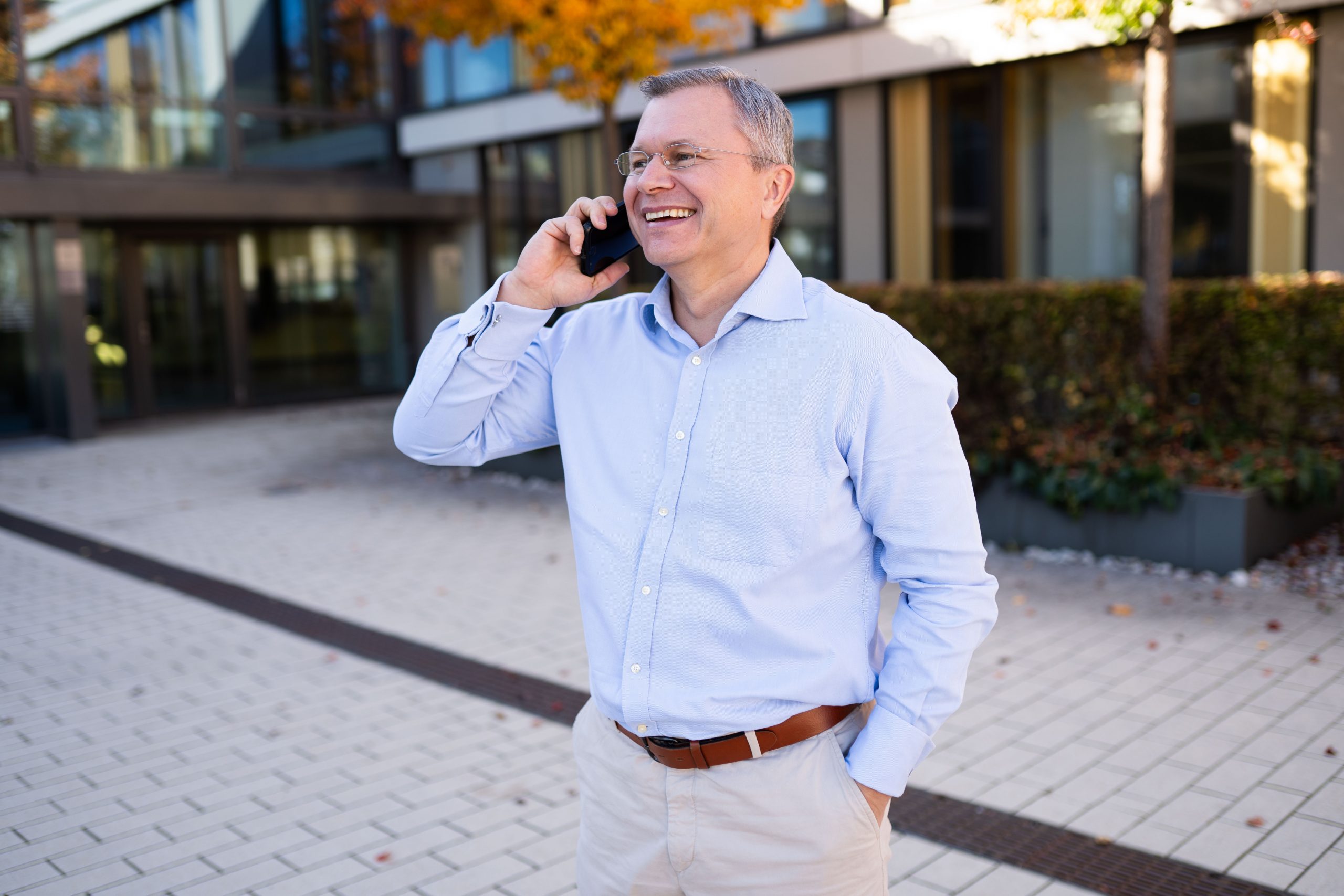 Stefan Siegl Gilching persönlich: Bürgermeister Stefan Siegl im hellblauen Hemd telefoniert lachend im Freien.